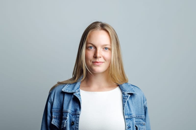 Headshot of Emma Larson in a denim jacket over a white top against a grey background
