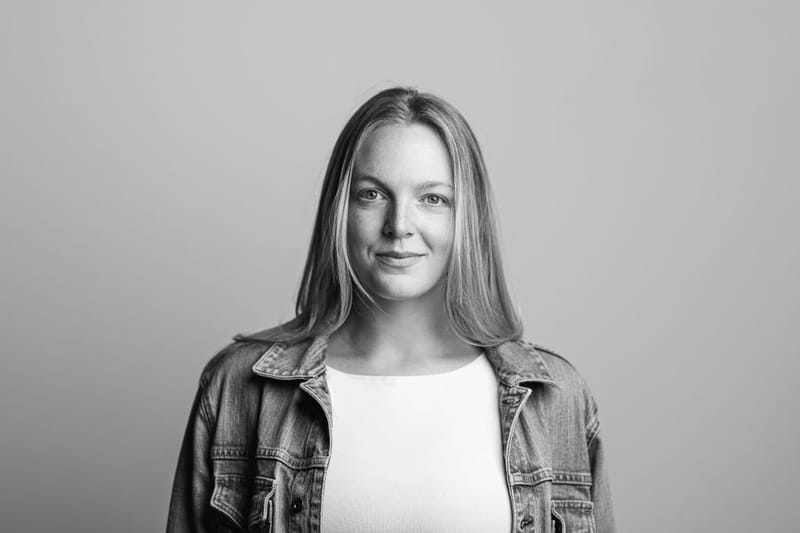 Black-and-white headshot of Emma Larson in a denim jacket over a white top